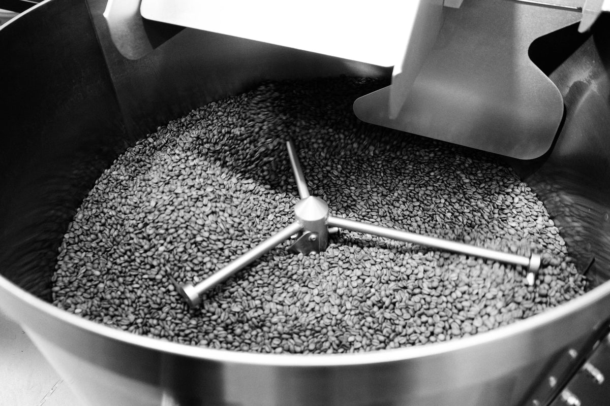 Kaffeebohnen im Kühlsieb des Rösters, der Rührarm zieht seine Bahnen